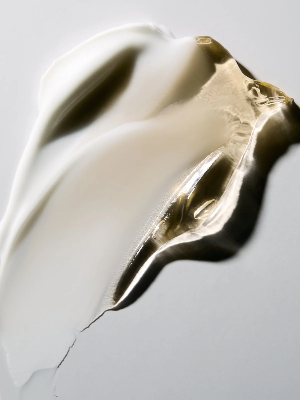 Macro shot of liquid gold metal swirling into a feather-like point on a white background, by Adrianna Favero.