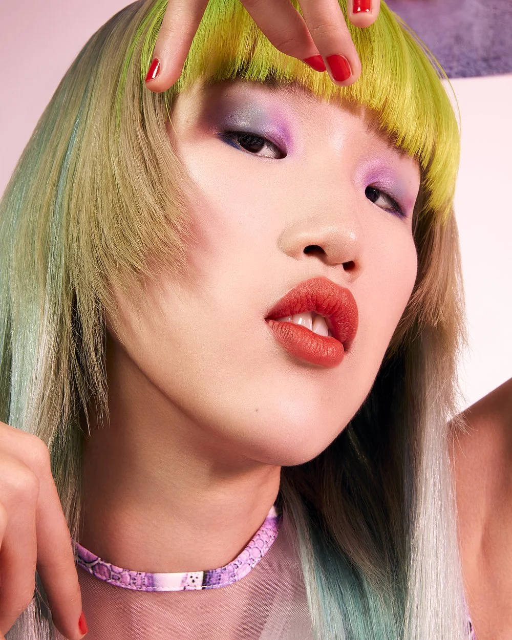 Person with colorful hair and makeup, wearing a purple choker.