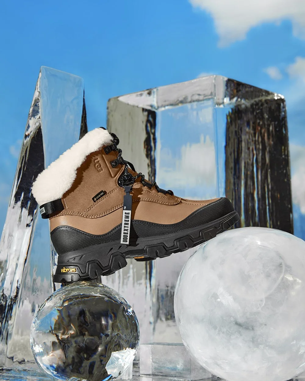 A brown winter boot with a fluffy white lining and thick sole displayed on a clear block with a blue sky background.