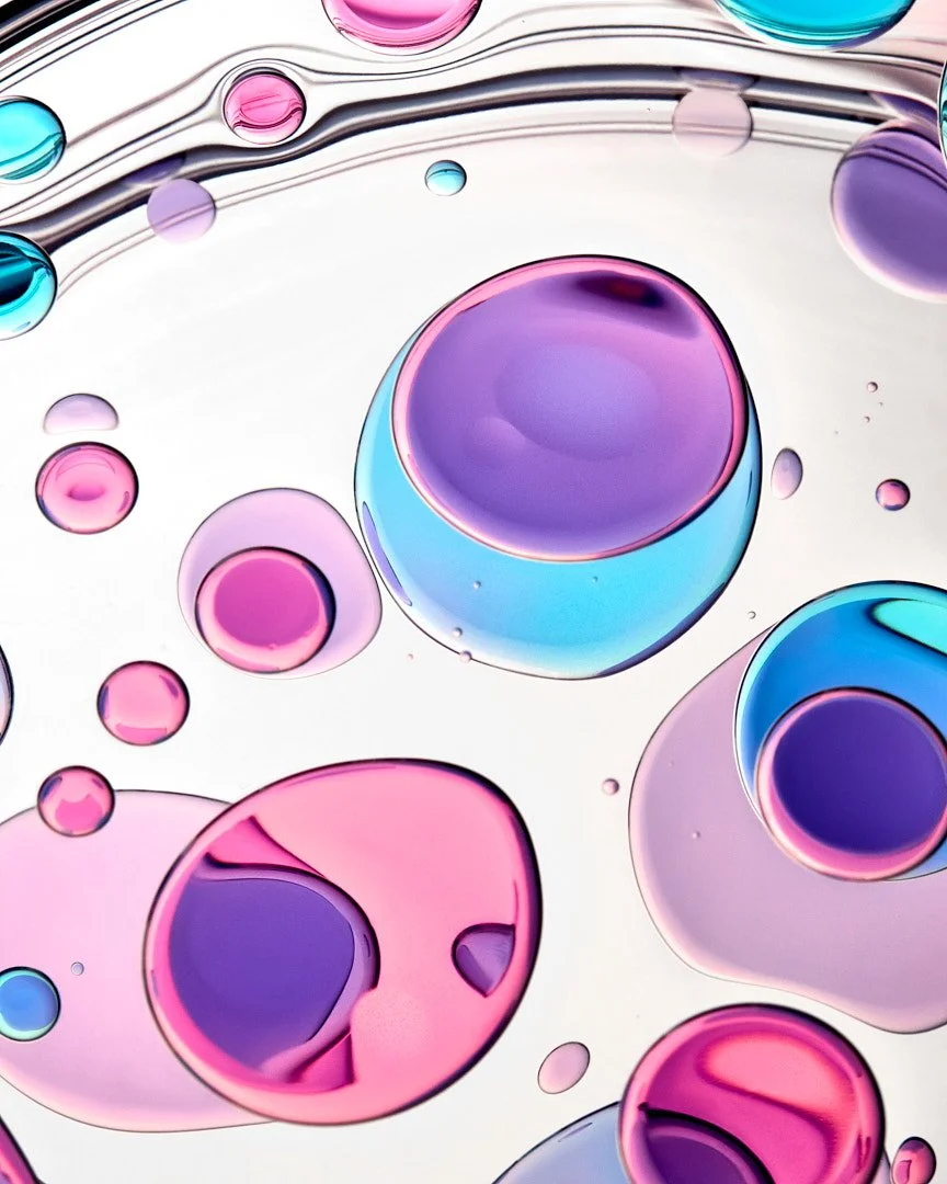 Abstract macro shot of colorful pink, purple, and blue cosmetic gel bubbles, by Adrianna Favero.