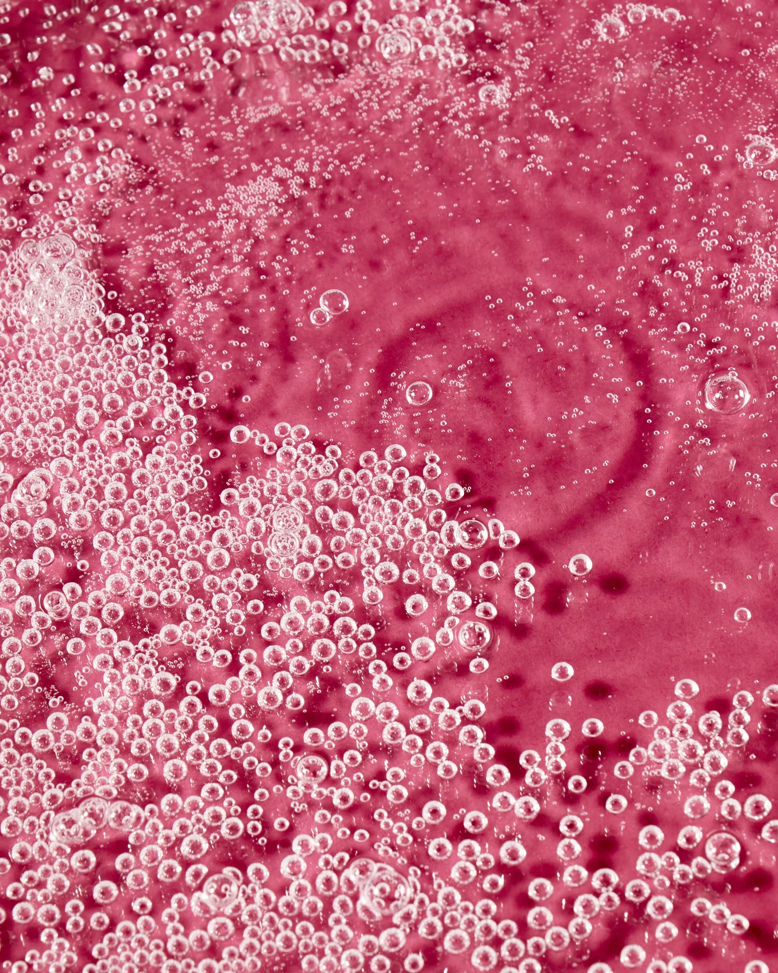 Close-up of fizzy bubbles on a pink liquid surface