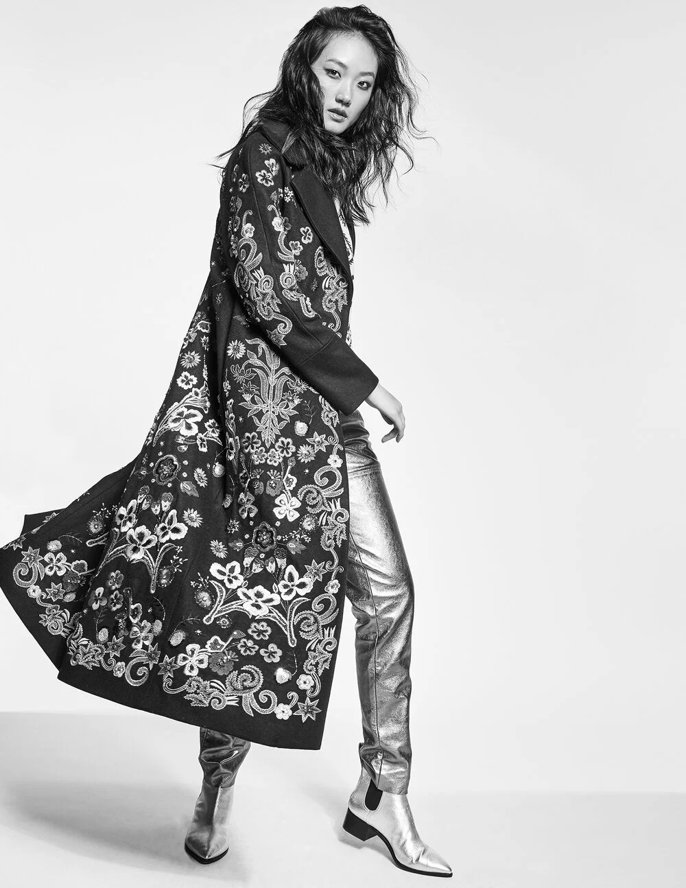 Fashionable person in patterned long coat and metallic pants
