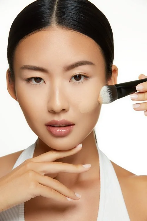 Lancome complexion makeup tutorial: model blending foundation onto her cheek with a makeup sponge applicator, photographed by Adrianna Favero.