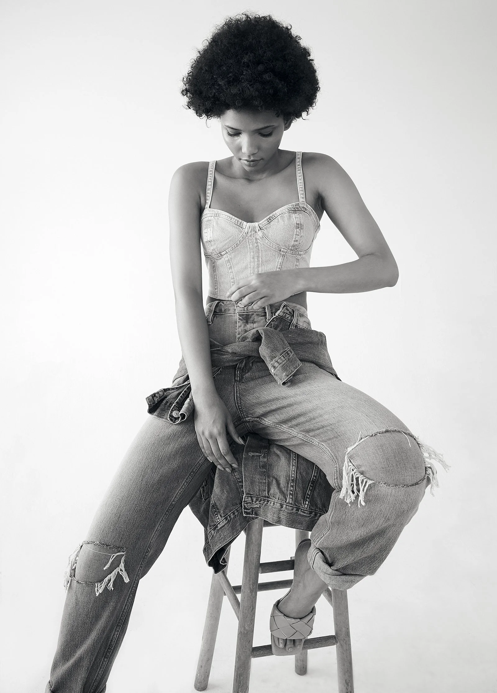 Woman sitting on stool in denim outfit, black and white