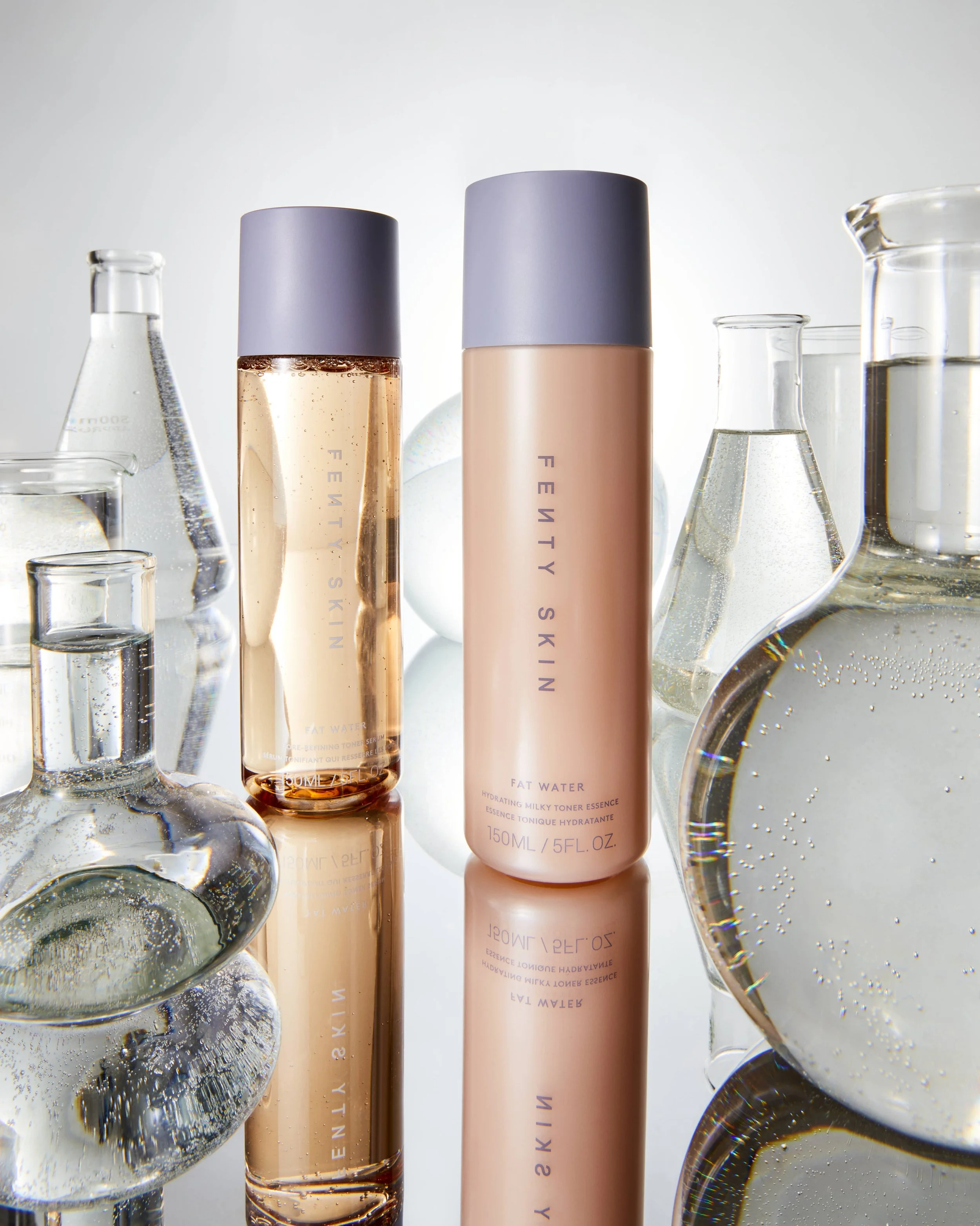 Fenty Skin Fat Water hydrating milky toner essence bottles surrounded by glass laboratory equipment.
