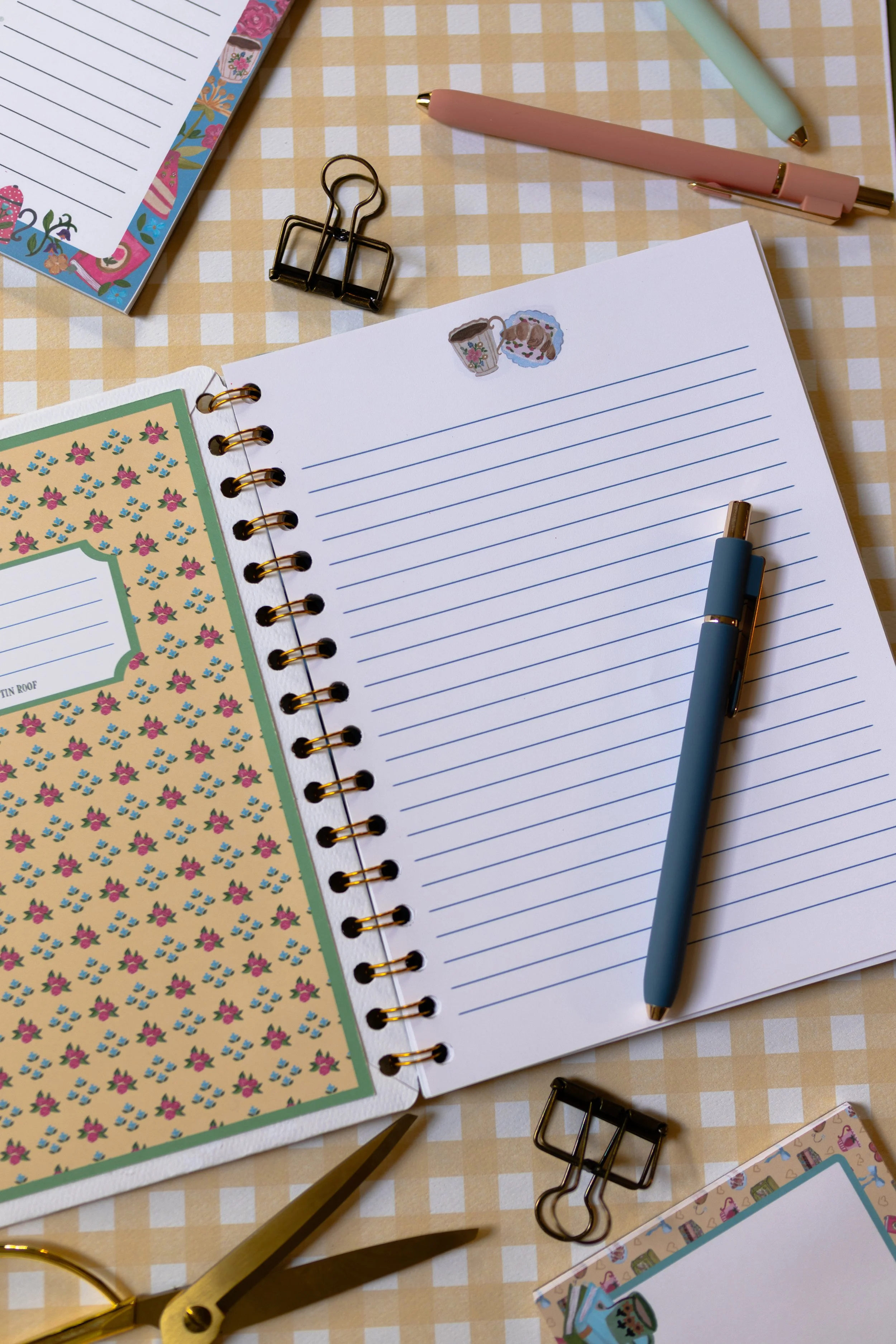 Open notebook showing ruled pages with premium gold double spiral binding.