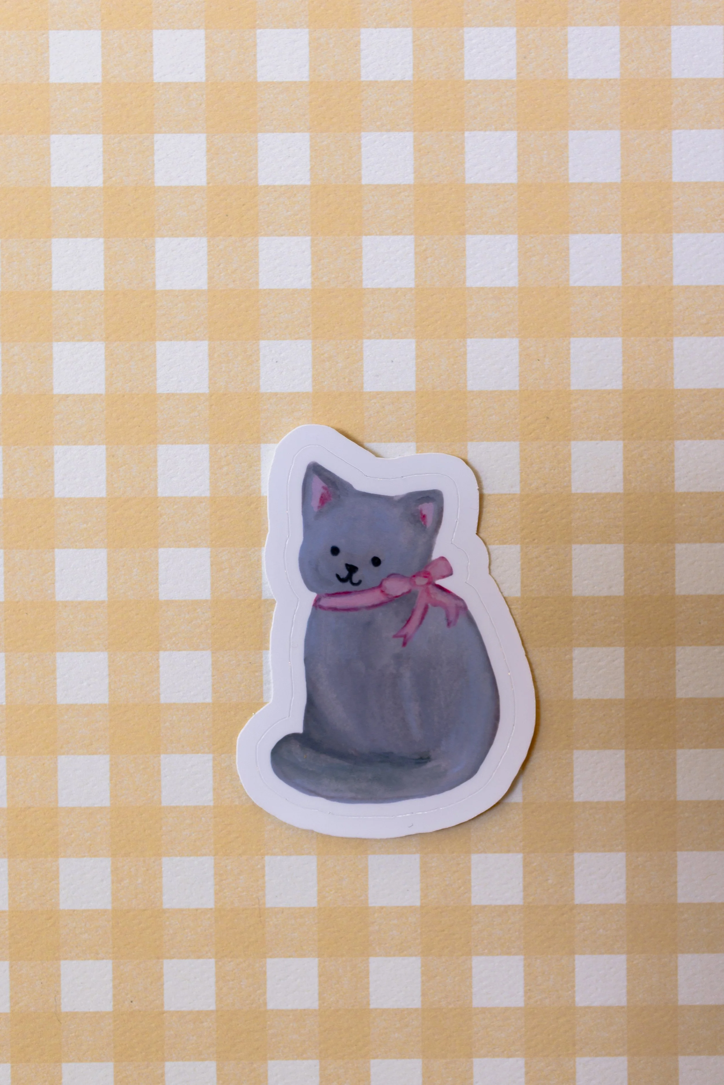 George the cat with pink bow die cut sticker featuring original artwork. Perfect for journals, planners, scrapbooking, and decorating everyday items.