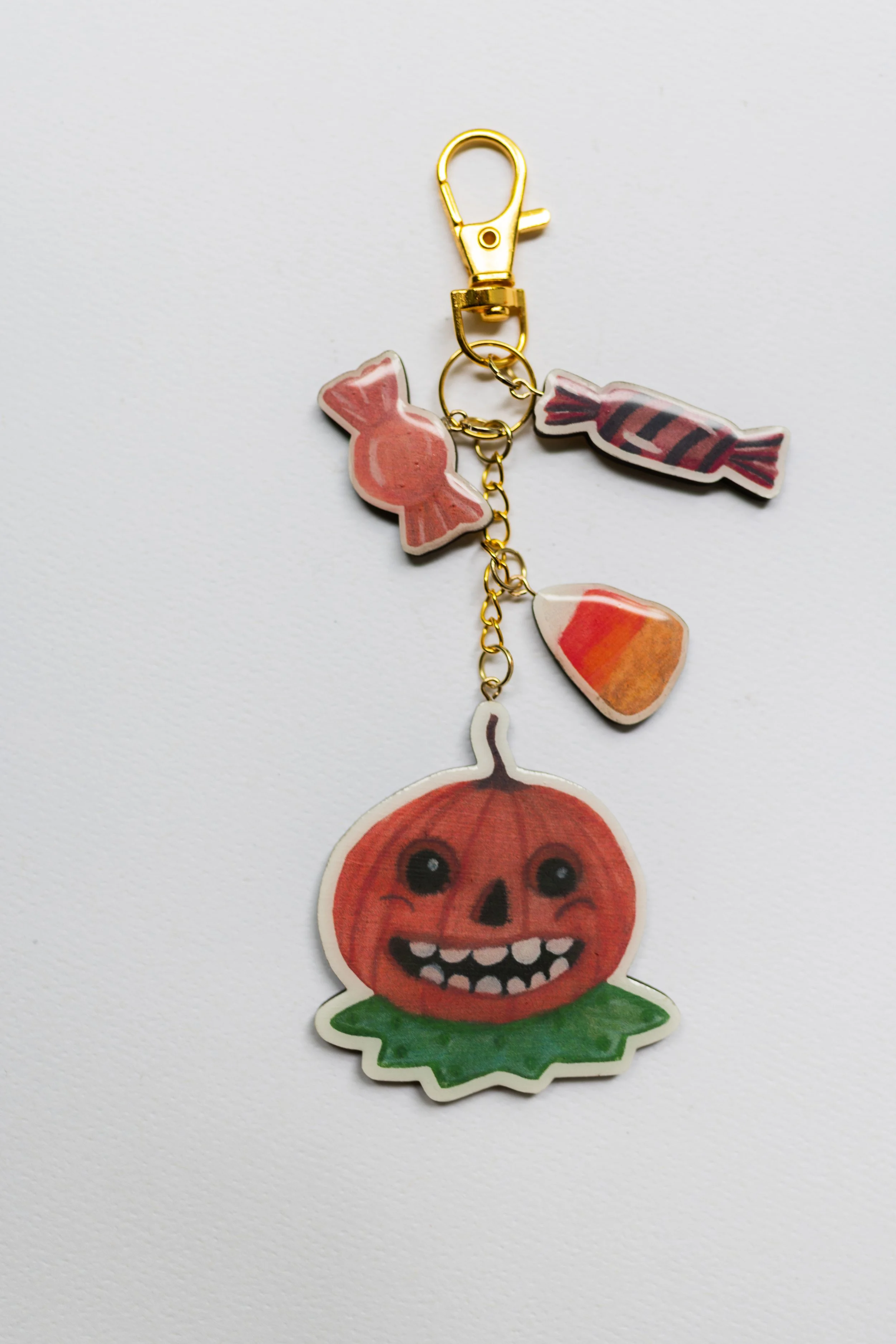 Vintage Halloween wooden keychain featuring a grinning pumpkin character with illustrated candy charms.