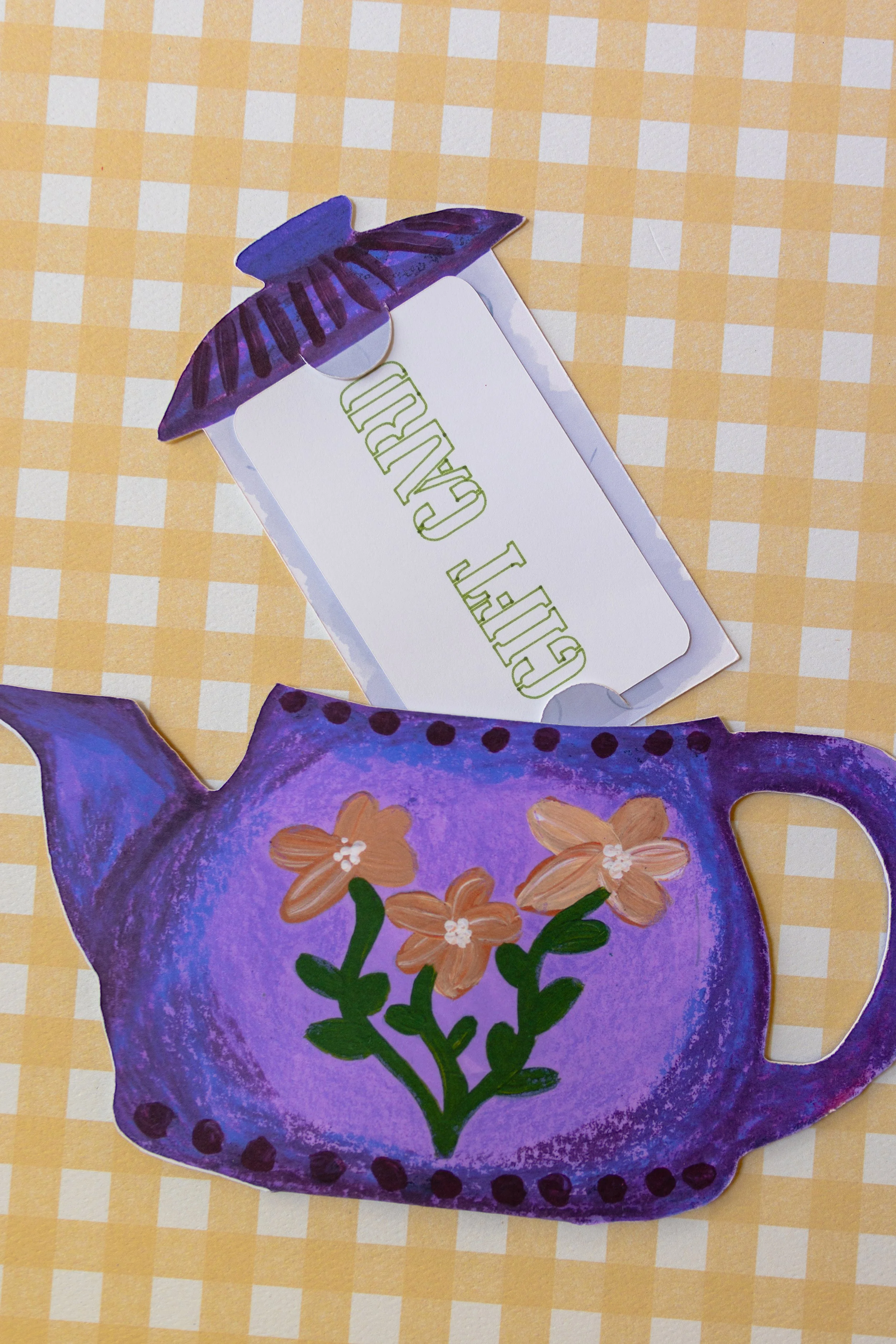 Interactive floral teapot gift card holder featuring a removable tea bag that hides a standard-sized gift card.