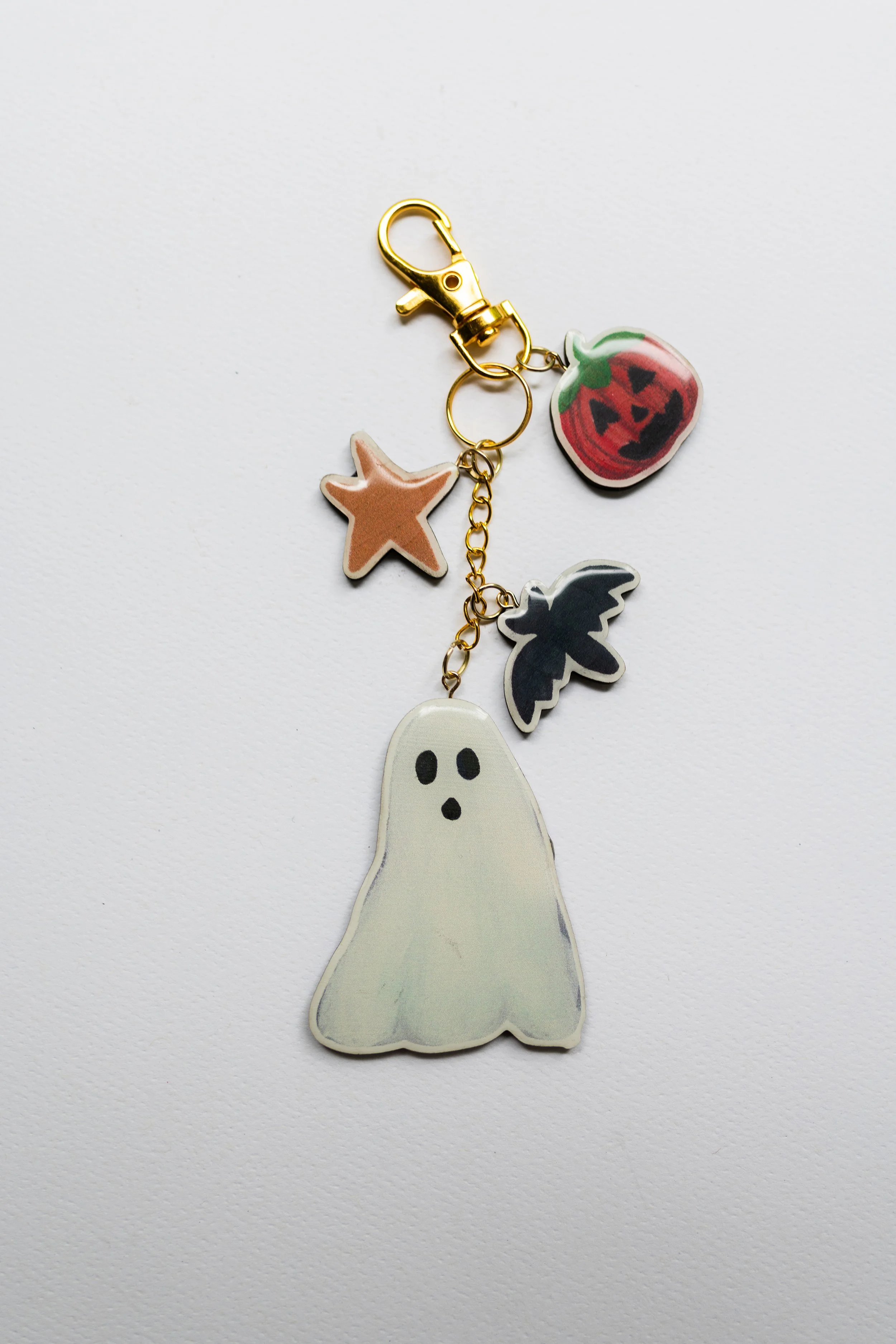 Wooden Halloween keychain featuring a white ghost with pumpkin, bat, and star charms.