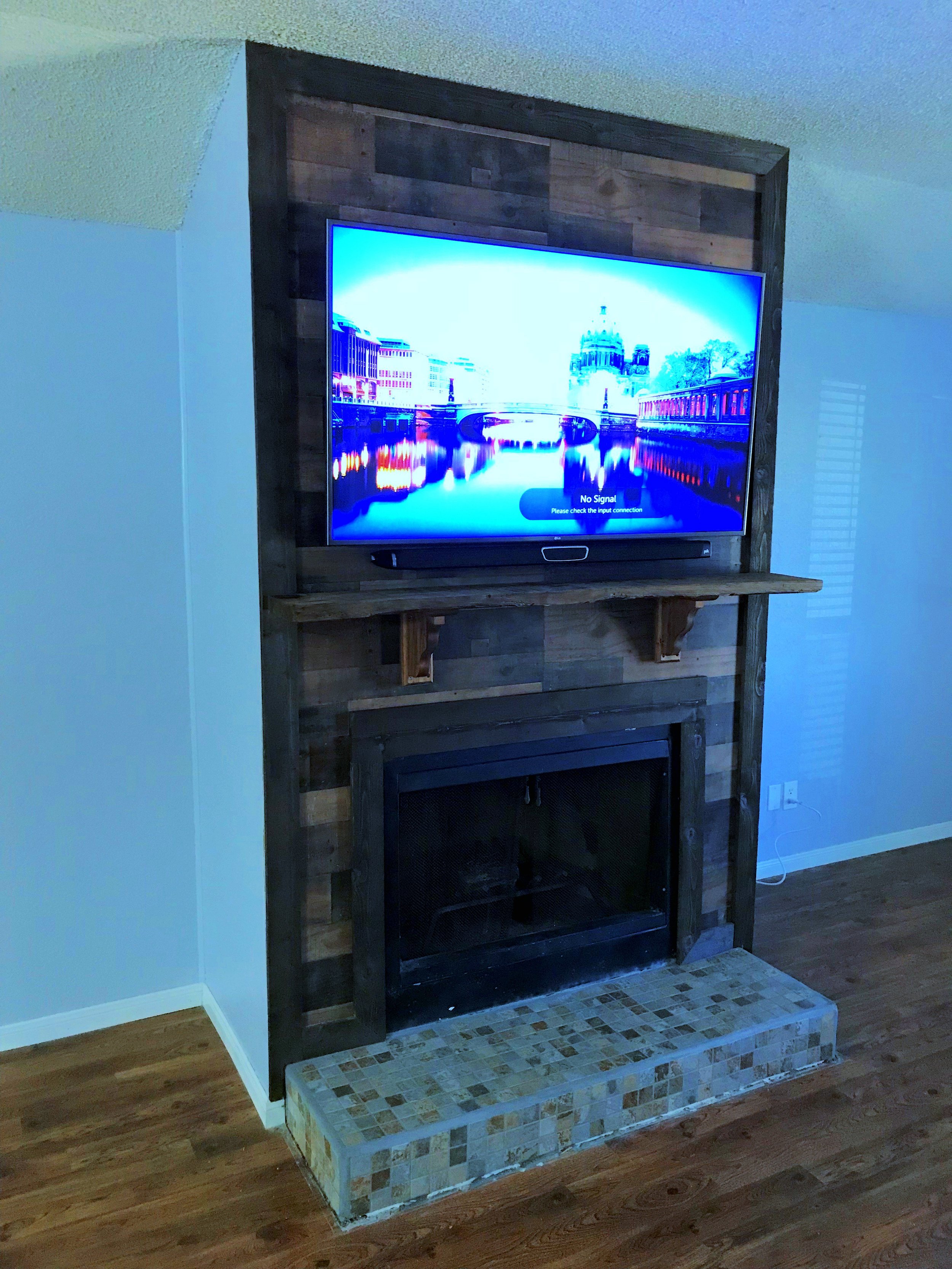 65' TV mounted above the mantle on a wood paneled fireplace