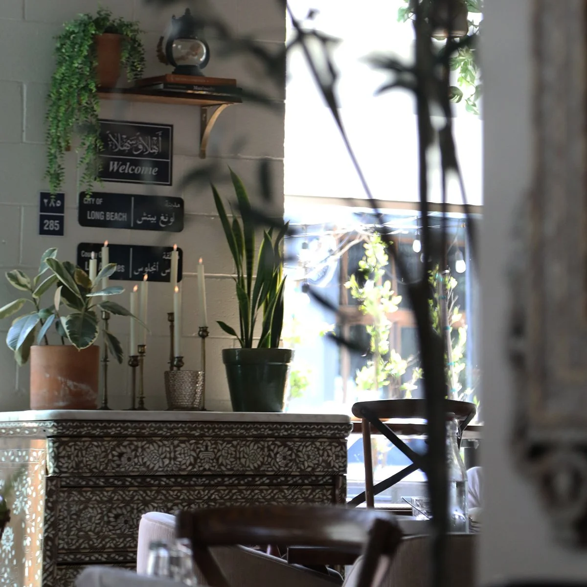 alt="A decorative credenza in Ammatoli's dining room displayed with plants, candles, and vintage-style Levantine signs"