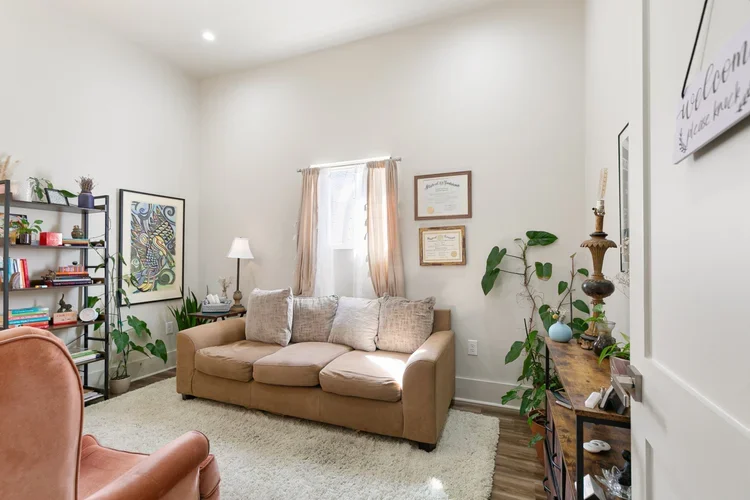 boutique commercial private office space new orleans for rent affordable office rental brown couch with white pillows open natural light windows with pink curtains framed certificates framed art plants in office pink leather armchair white fluffy rug