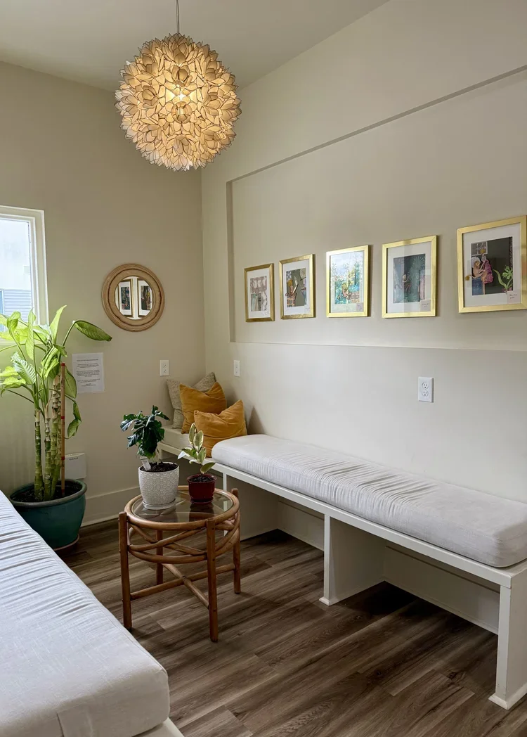 private boutique office space rental new orleans louisiana waiting room lobby framed art light fixture white bench with white cushion gold framed art coffee table plants 