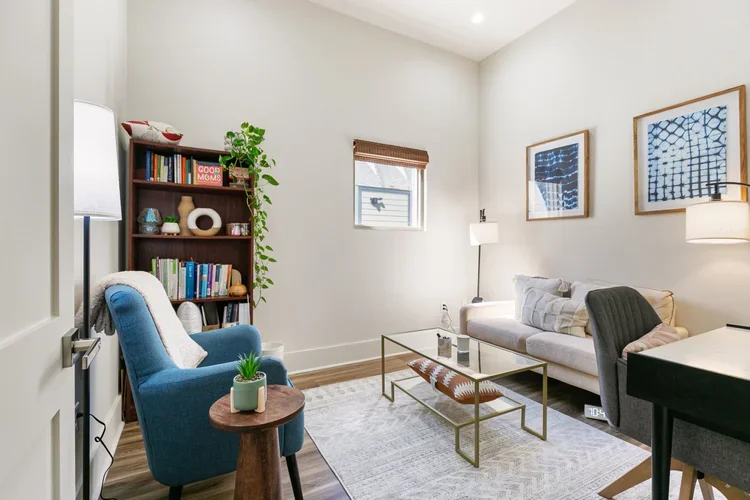 blue armchair private office rental space white couch white and gray rug white walls bookshelf gold and glass coffee table art on walls natural light office private commercial office rental new orleans