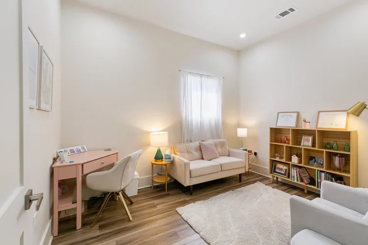 private boutique commercial office rental new orleans white rug wooden bookshelf white chair pink desk pink sofa loveseat 