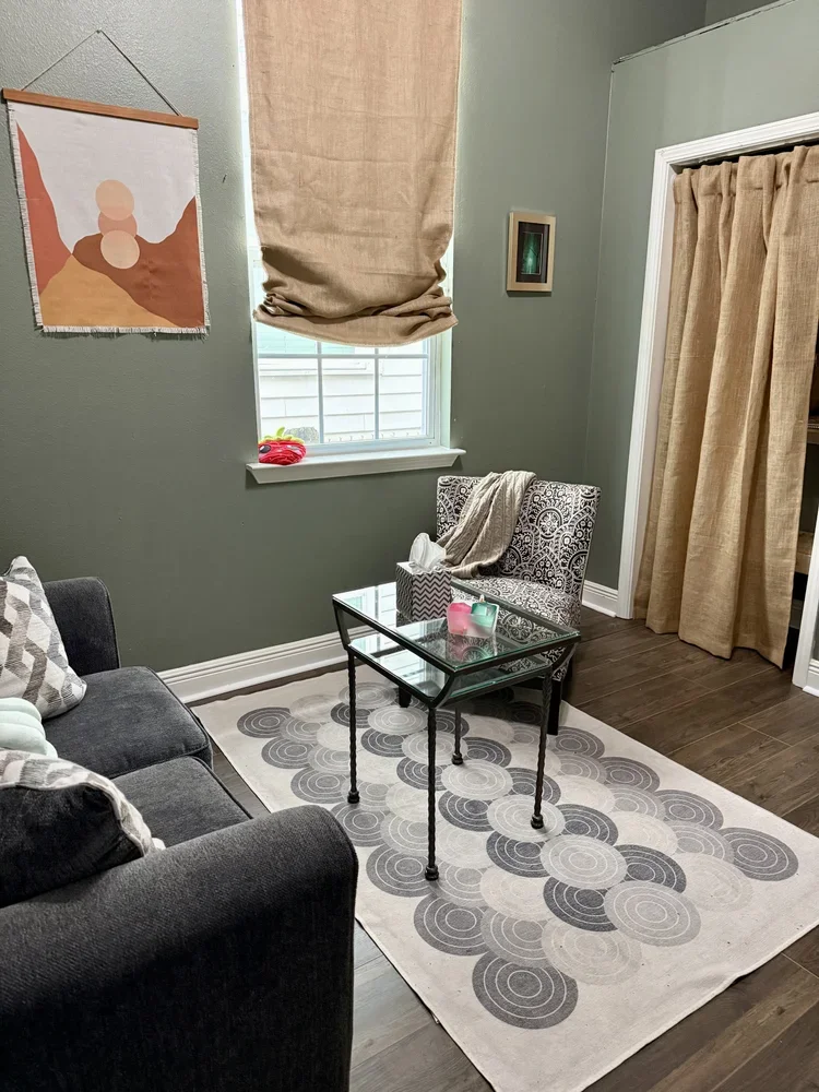 gray couch gray rug green walls with white trim and orange linen curtains with a black and white arm chair and textile decor private boutique commercial office rental space new orleans  