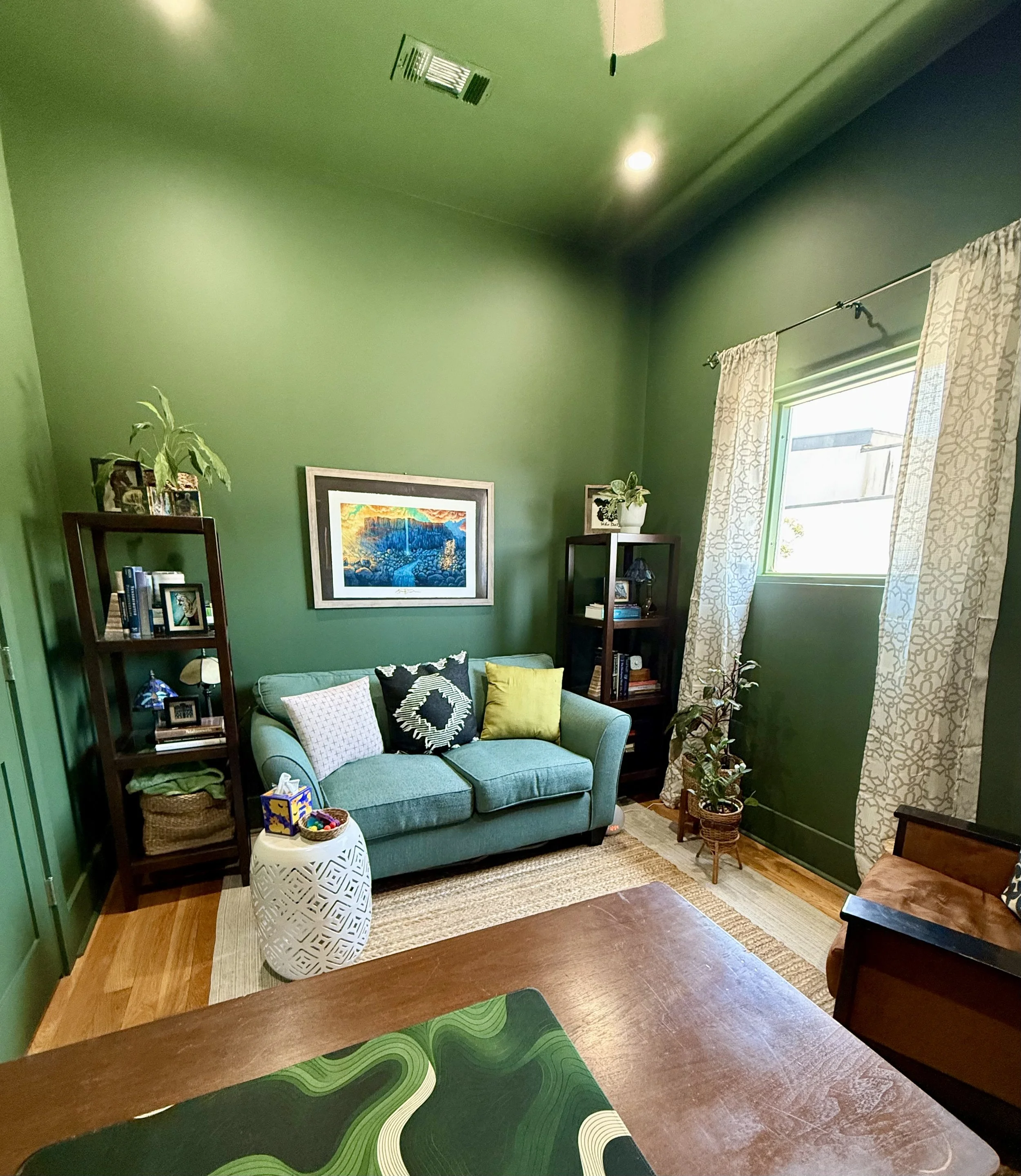 green wall office space rental green couch desk armchair white curtains table plant stand wall art