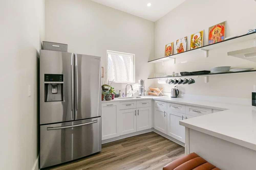 kitchen shared office space boutique private office rentals commercial rental new orleans artwork natural light mugs white countertops white cabinets stainless steel fridge metal fridge coffee maker sink cooking mugs