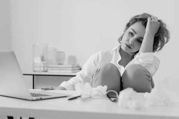 woman at desk looking overwhelmed