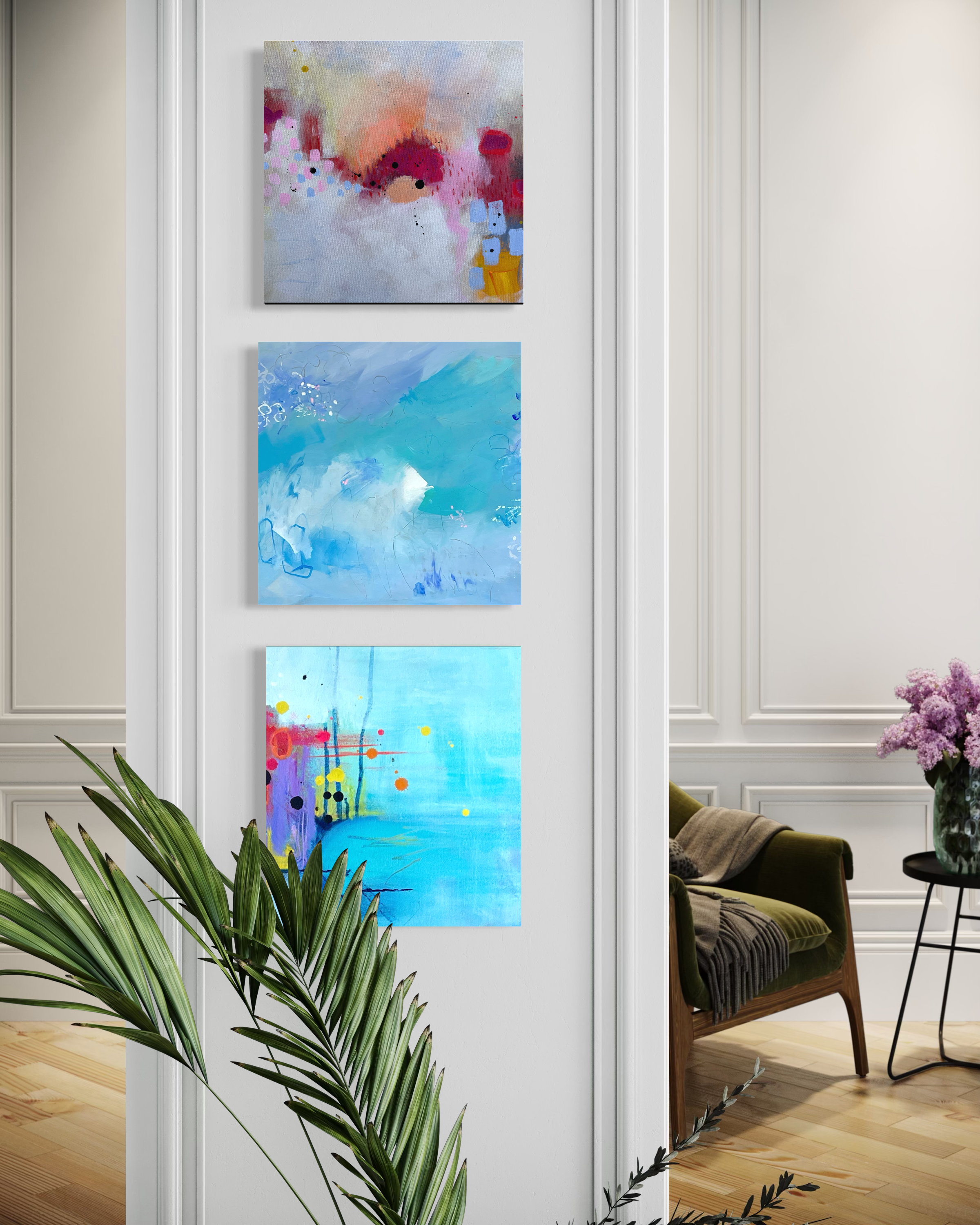 Three soft abstract paintings by Anne Whately stacked vertically in pale blues and pinks on a white panelled wall.