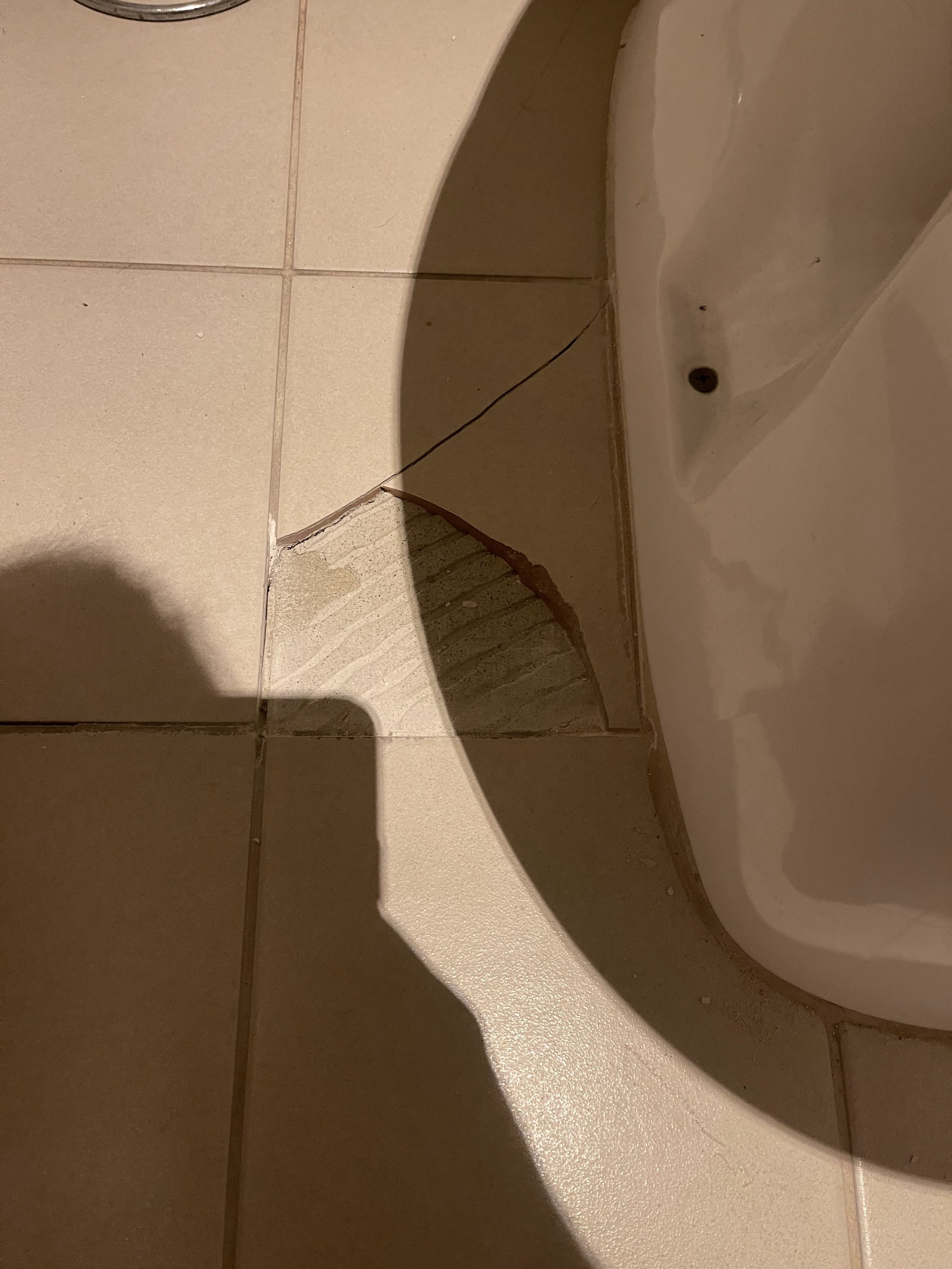 Floor tiles, a crack near the base of a toilet from a toilet removal.