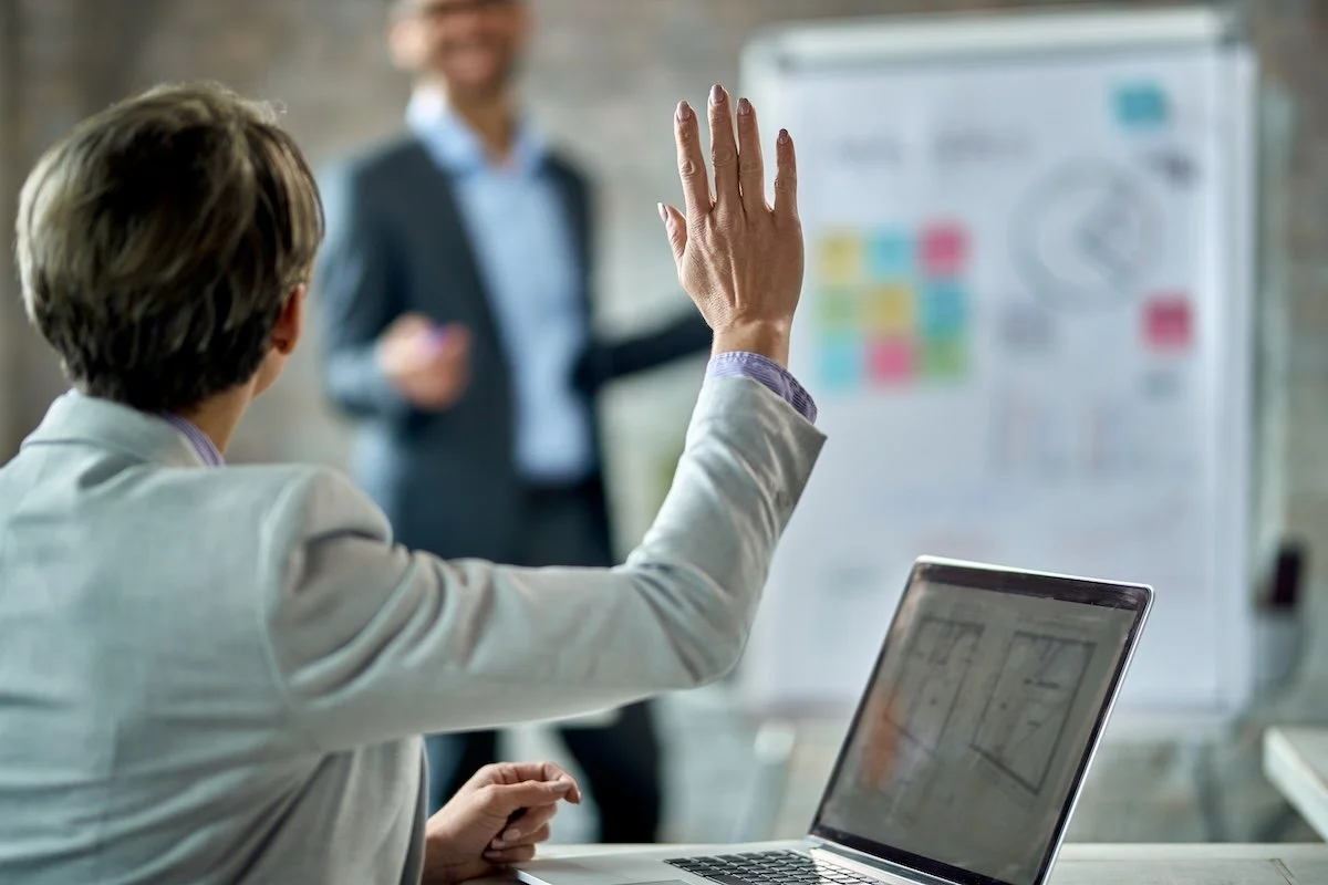 back-view-female-entrepreneur-raising-hand-answer-question-business-presentation-office.jpg