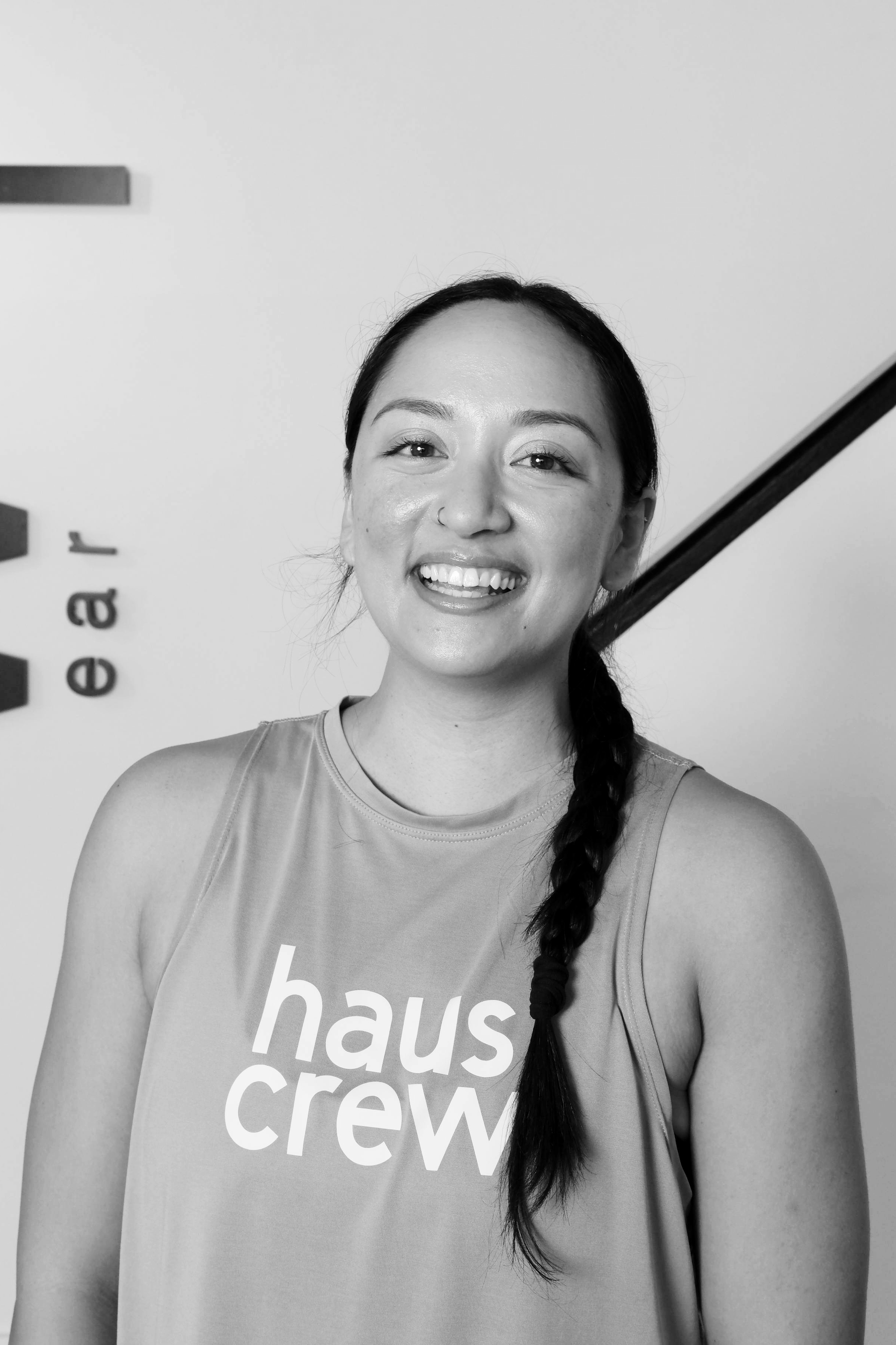 A close up, black and white photo of a woman with a high ponytail smiling at the camera.