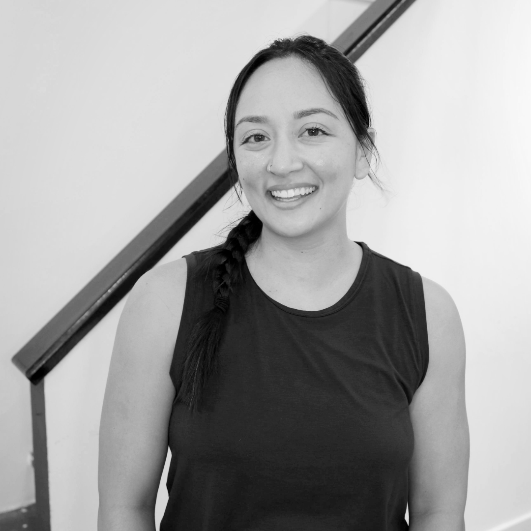 A close up, black and white photo of a woman with a high ponytail smiling at the camera.