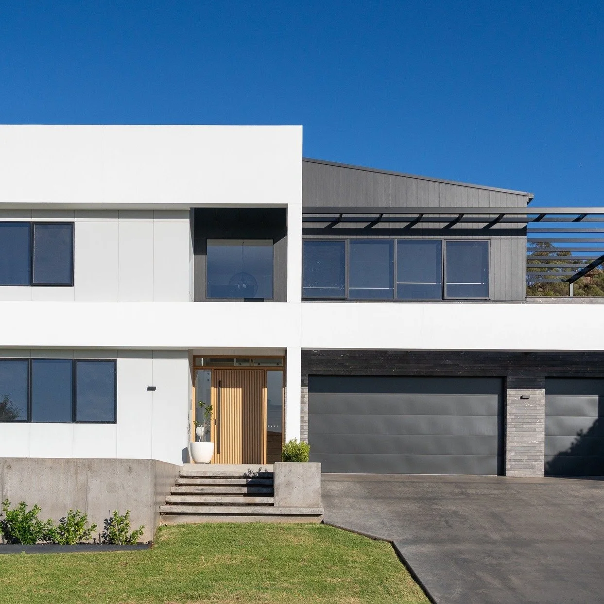 Moving from the bold exterior into the heart of the home, the interior continues the story of balance and refinement.
The staircase becomes a quiet statement — timber, glass, and black accents working together to create lightness and warmth. N