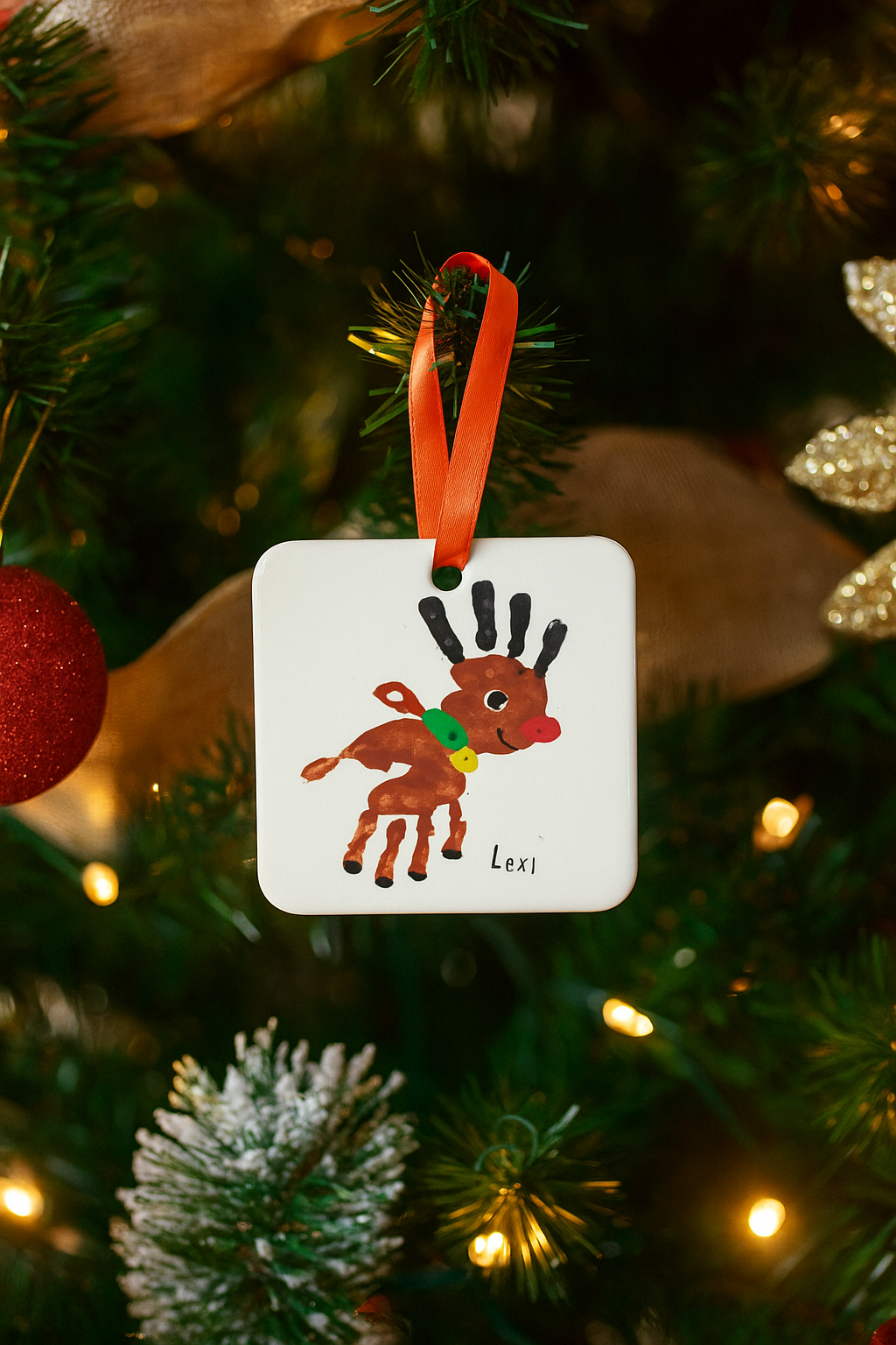 School christmas hanging decoration featuring childs original artwork and name hanging on a christmas tree with red ribbon