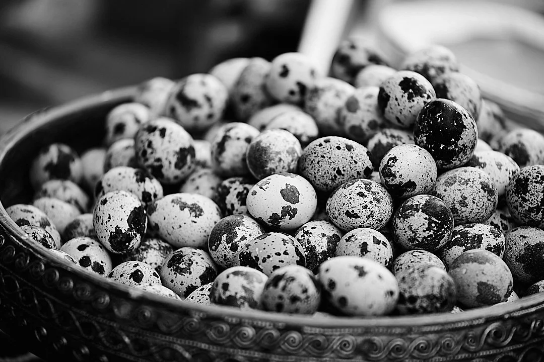 A bowl of quail eggs at a market stall. Small, speckled, arranged by no one, perfect anyway.