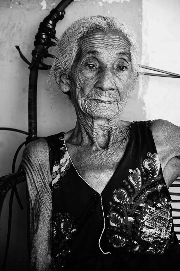 She sat with her hands in her lap and let me photograph her without asking why. Her face holds everything the dunes cannot — time, weather, loss, something close to peace. She has outlasted things that would have finished most people. She did not say