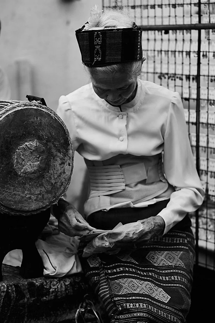 She sat beside the ceremonial drum in full traditional dress, sorting papers with the same quiet focus she would bring to any task. The costume was not a performance. It was just what she wore.