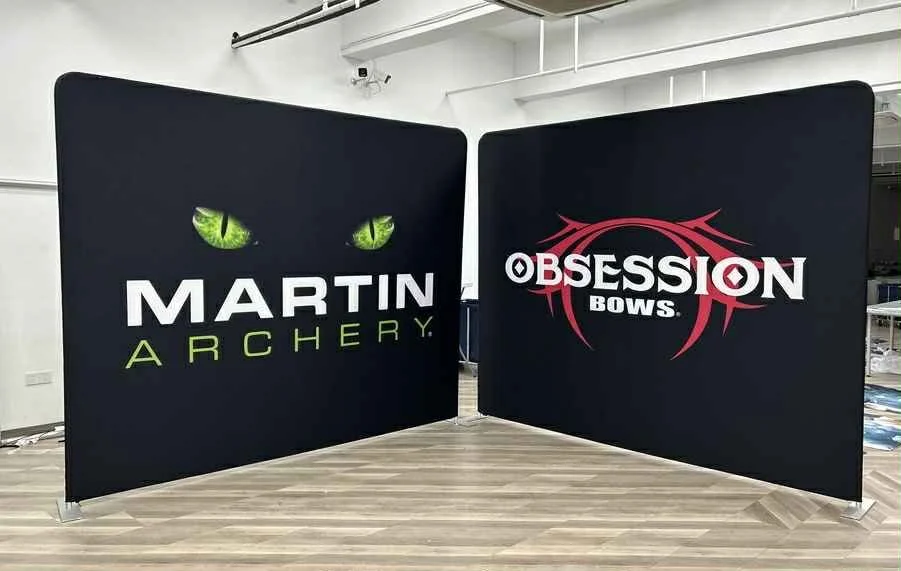 Two black display panels with logo and text. The left panel shows green cat eyes above the words "Martin Archery" in white and lime green. The right panel displays the words "Obsession Bows" in white and red with a stylized red bow graphic background