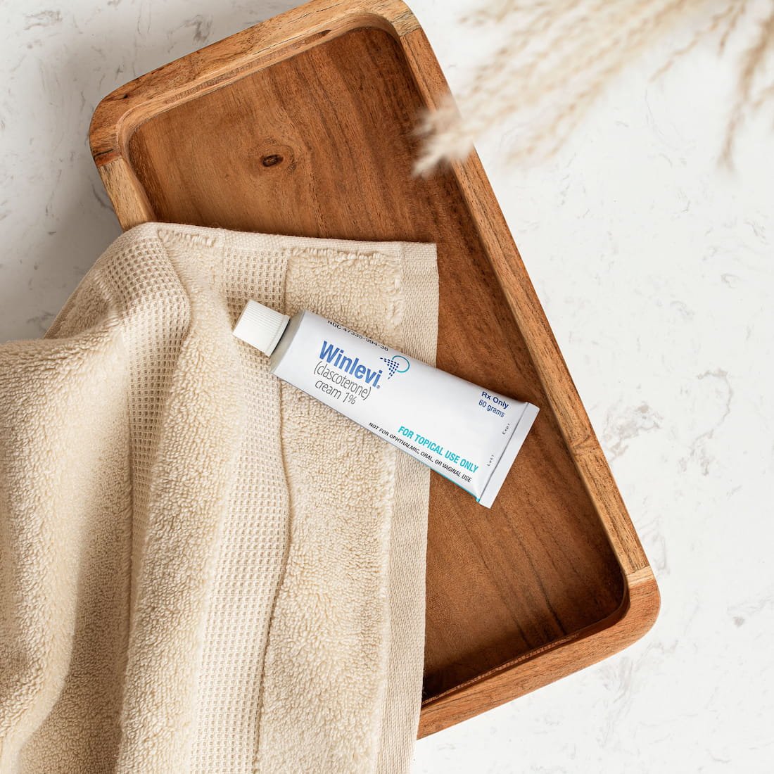 A tube of Wilnevi cream resting on a cream-colored textured towel inside a wooden tray.