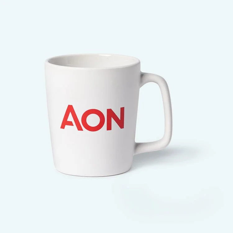 White coffee mug with red 'AON' logo on it, placed on a light-colored surface.