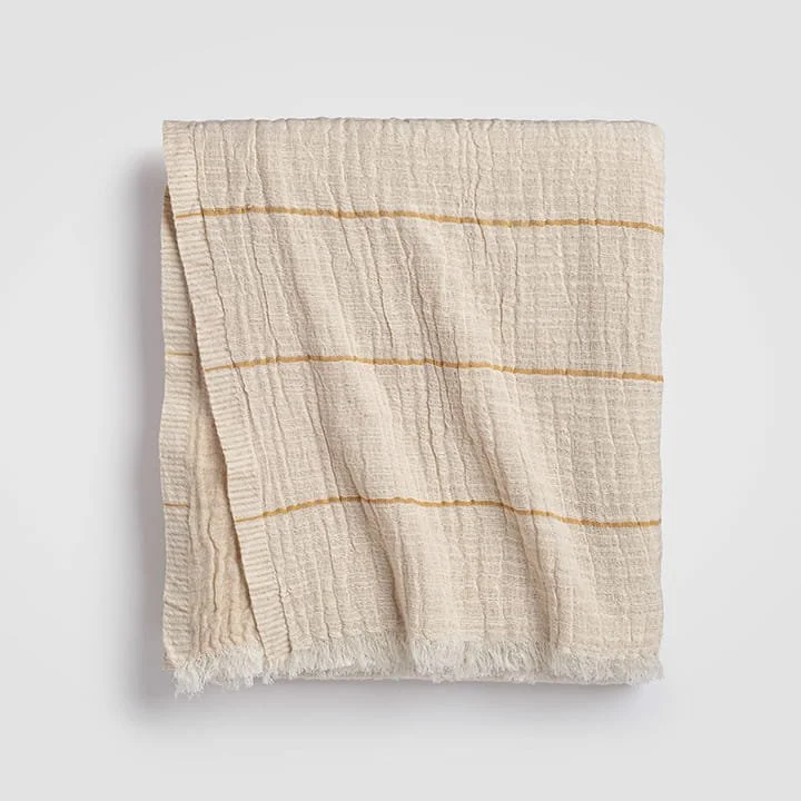Cream-colored woven cloth with horizontal yellow stripes, partially folded on a white background.