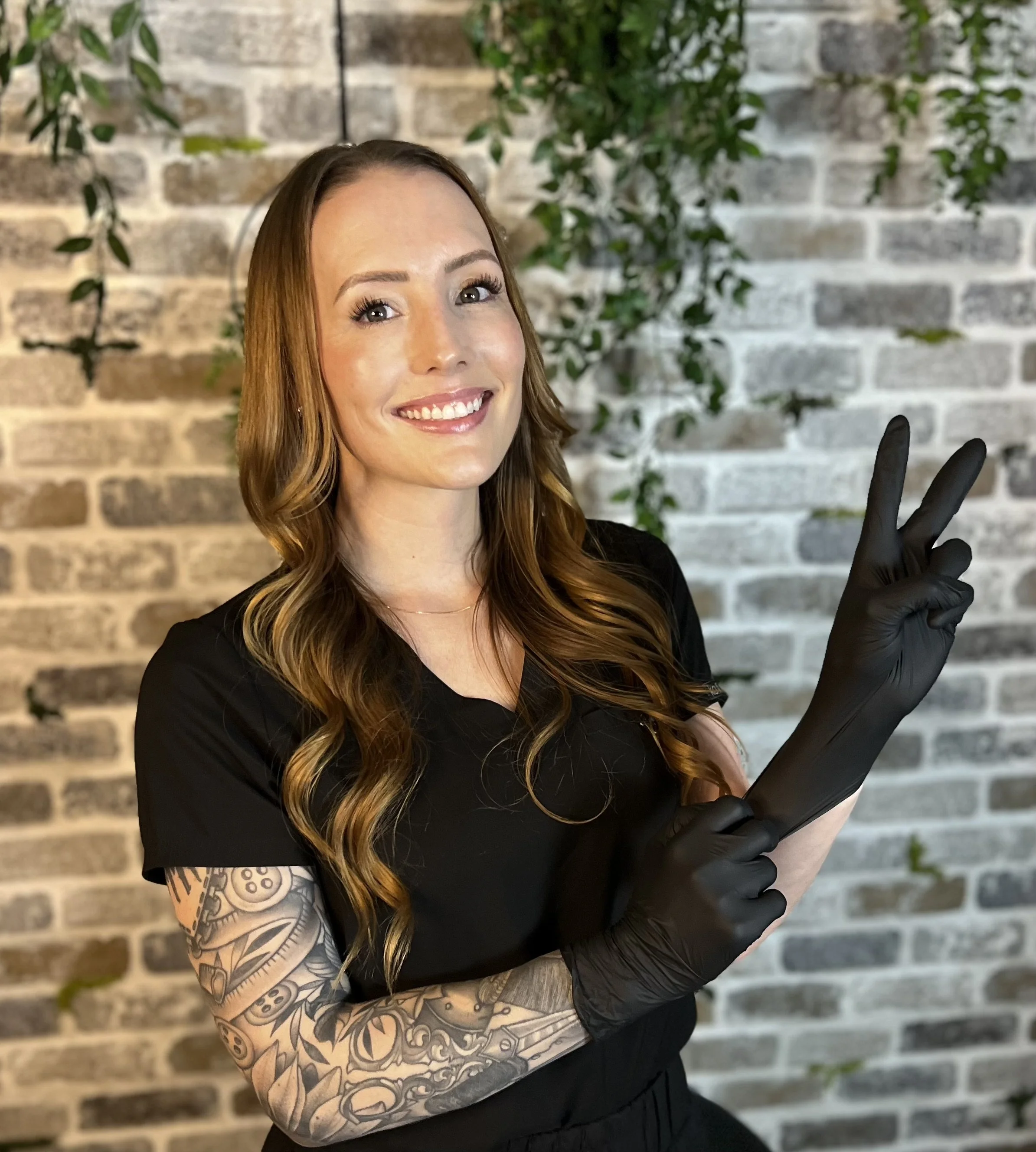 Woman smiling wearing black latex gloves and making a peace sign