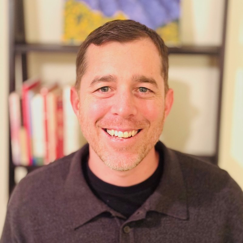 Smiling man in dark shirt. 