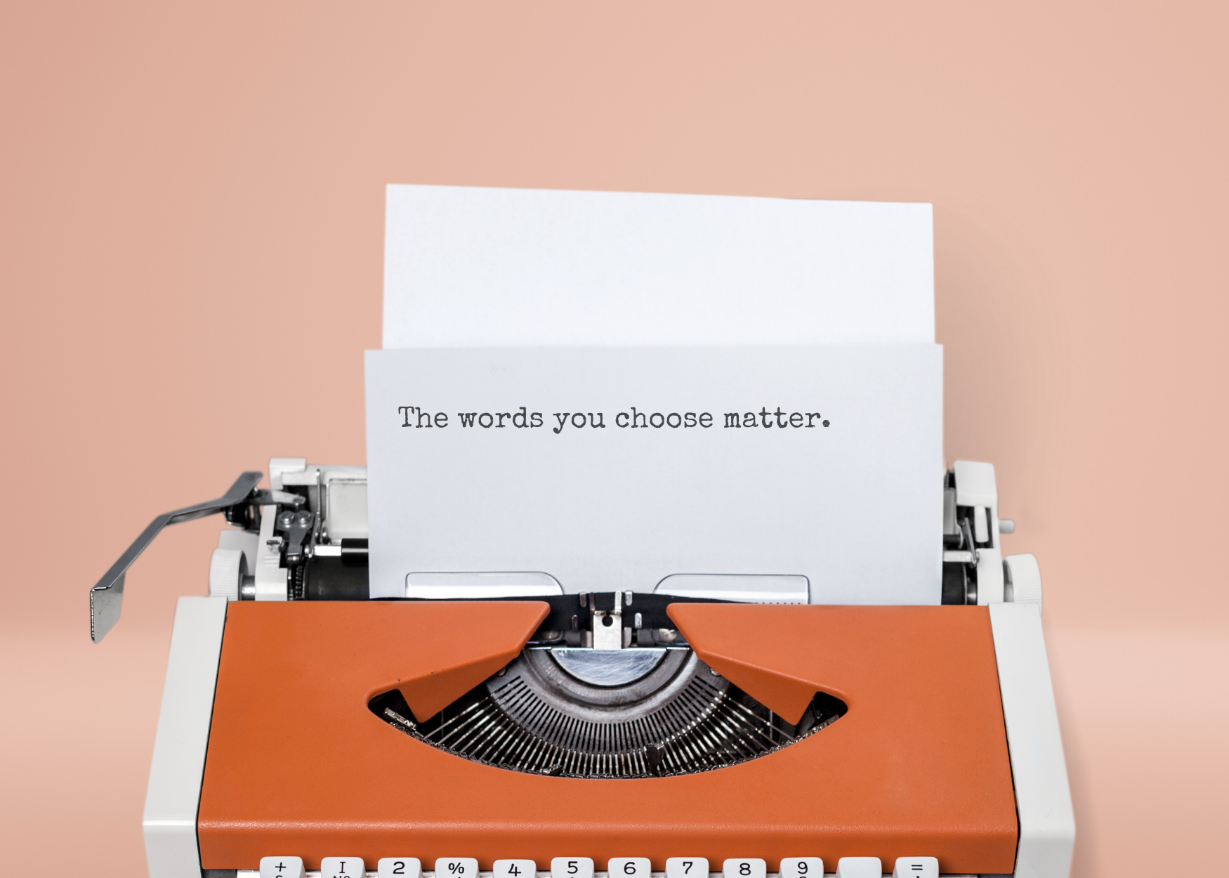 A typewriter with a page displaying the text "the words you choose matter," emphasizing the importance of language in inclusive marketing and brand communication.
