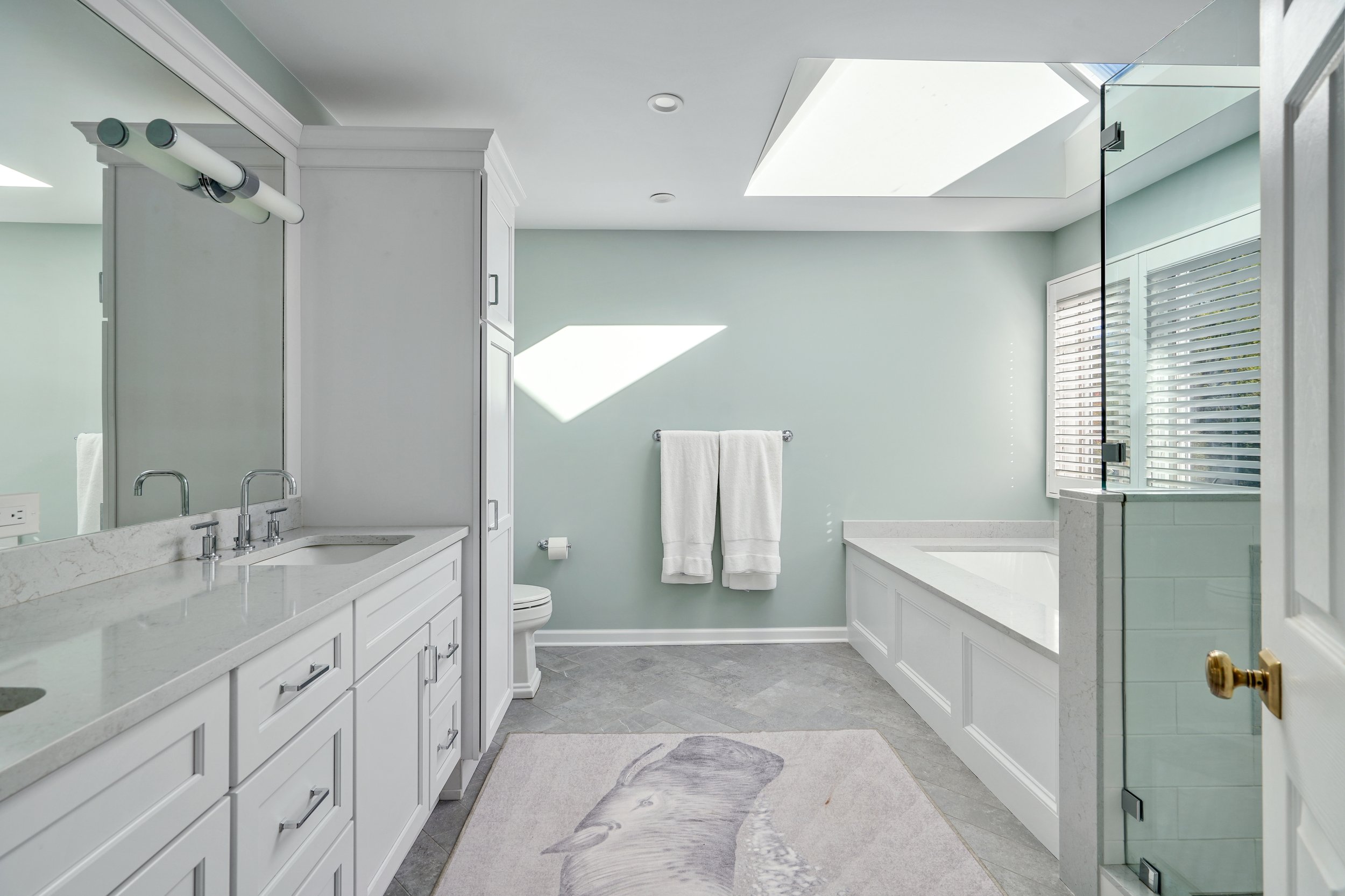 Primary bathroom, double under mount sink, glass shower, soaking tub, mudroom, laundry room, charcoal floor tiles, galley bathroom, light and airy.