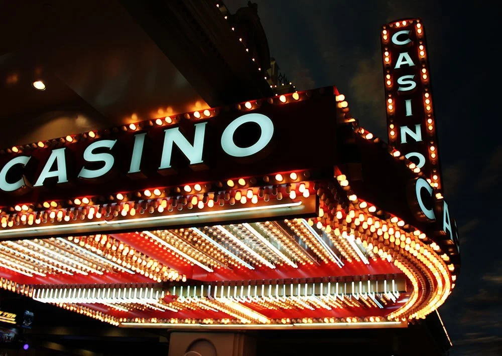 Illuminated casino marquee with large CASINO lettering and rows of colorful bulbs.