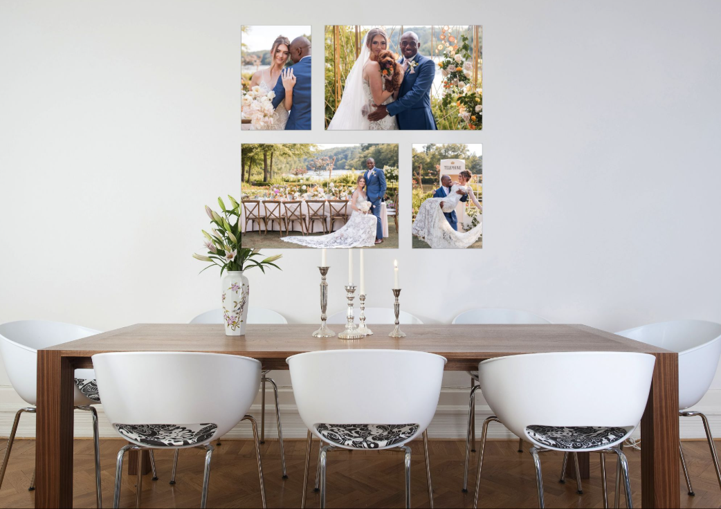 A dining room with a wooden table, six white chairs with floral cushions, a vase with flowers, and four candles. On the wall are five wedding photos of a bride and groom in outdoor settings.