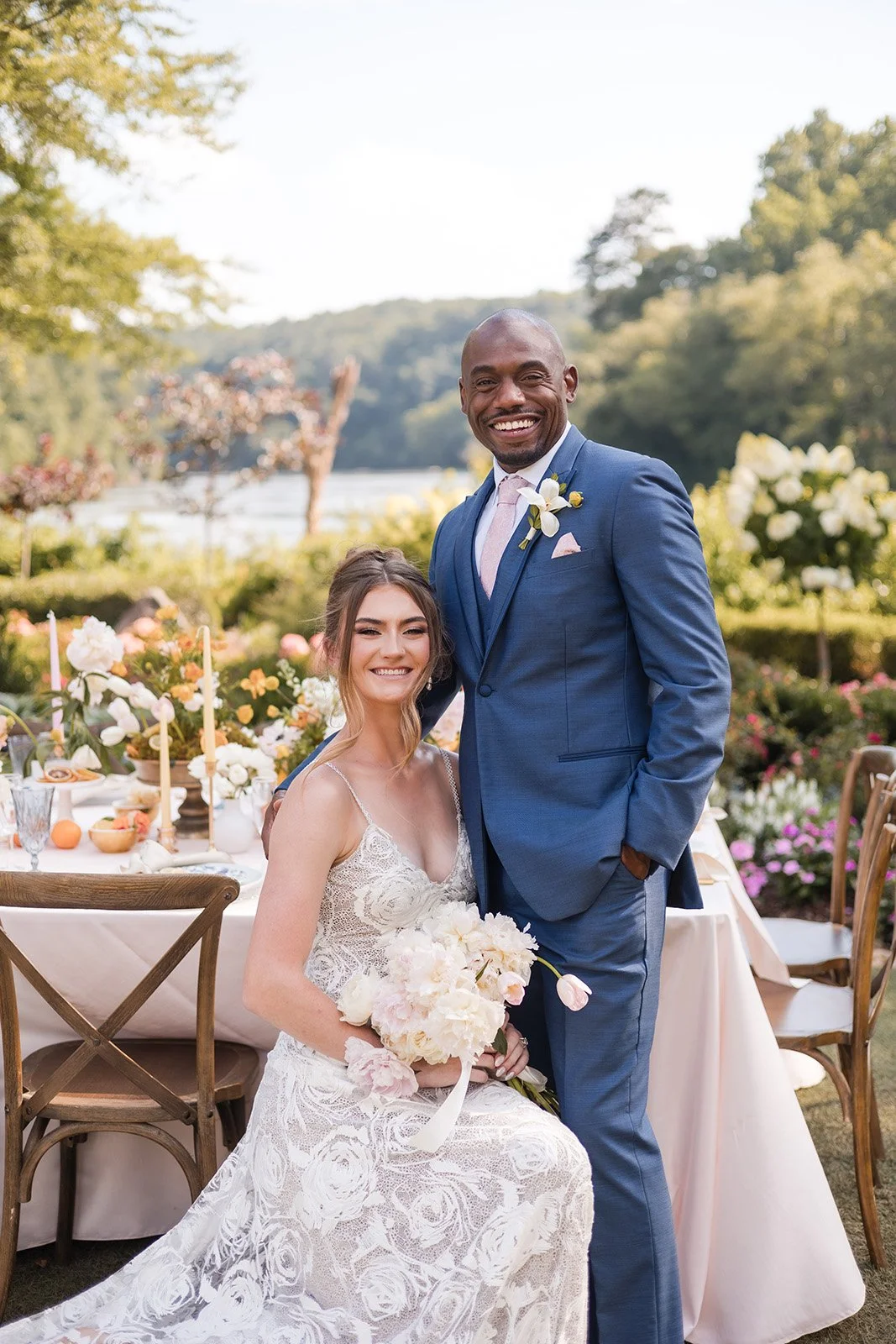 A floral arch for a wedding ceremony with candles on steps in a rustic venue with wooden walls and ceiling. Green drapes frame the arch.