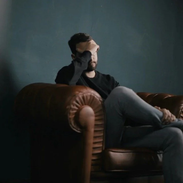 Man in chair with hand on forehead