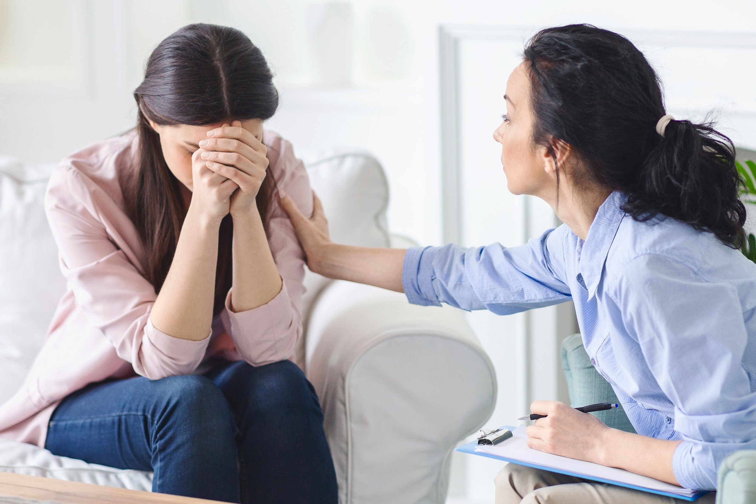 A sad patient is comforted by a caring therapist