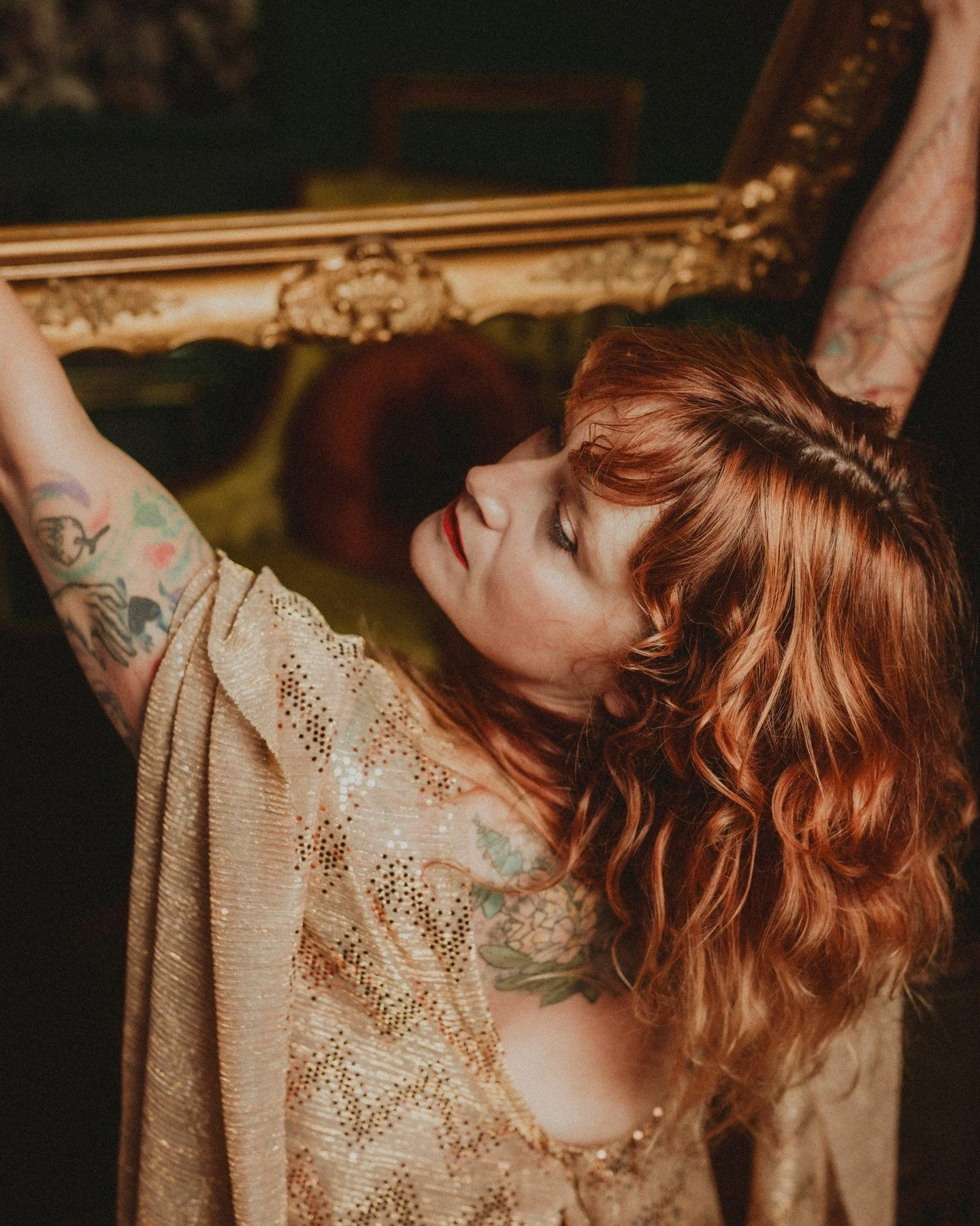 YOU are the ✨art✨ the world needs more of 🖼️
.
.
.
.
.
.
[Image Description: A white woman with wavy red hair and bangs is wearing a gold sequined goddess-y dress with a low-cut back and is holding a large ornate gold frame up as she looks over her 
