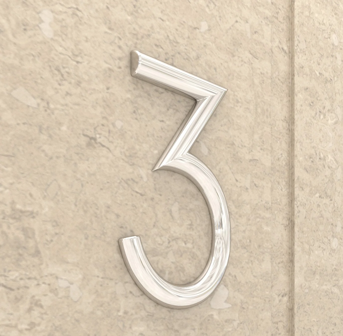 Close-up of a metallic house number 3 mounted on a beige concrete wall.