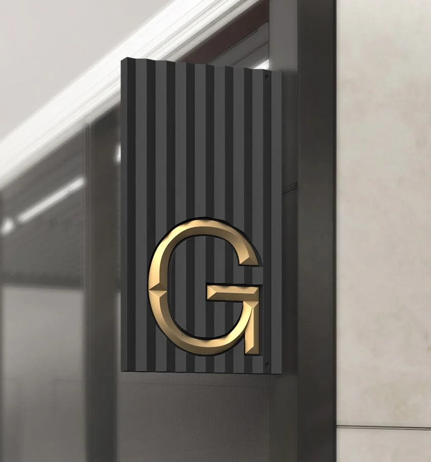A modern black wall panel with vertical ridges and a gold emblem of a stylized letter G.